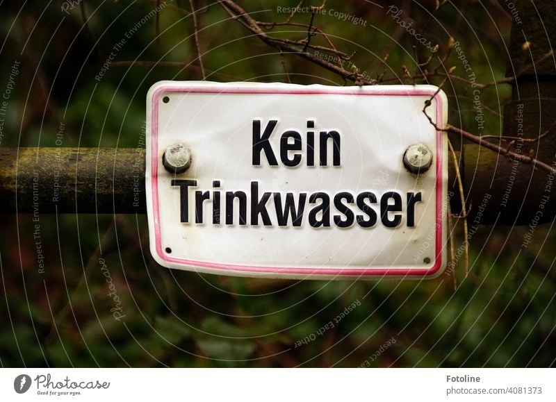 "No drinking water" is written on an old dented tin sign. Old Metal Iron Rust Deserted Exterior shot Close-up Detail Day Colour photo Subdued colour