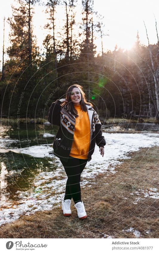 Cheerful young woman on pond in forest happy hiker cheerful traveling joyful tourism meadow snow weather leisure footpath trees sunlight female lifestyle