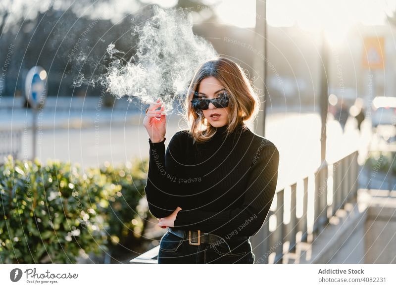 Stylish woman lighting cigarette near metro station smoking street style sunny daytime female city urban underground entrance young lifestyle leisure rest relax