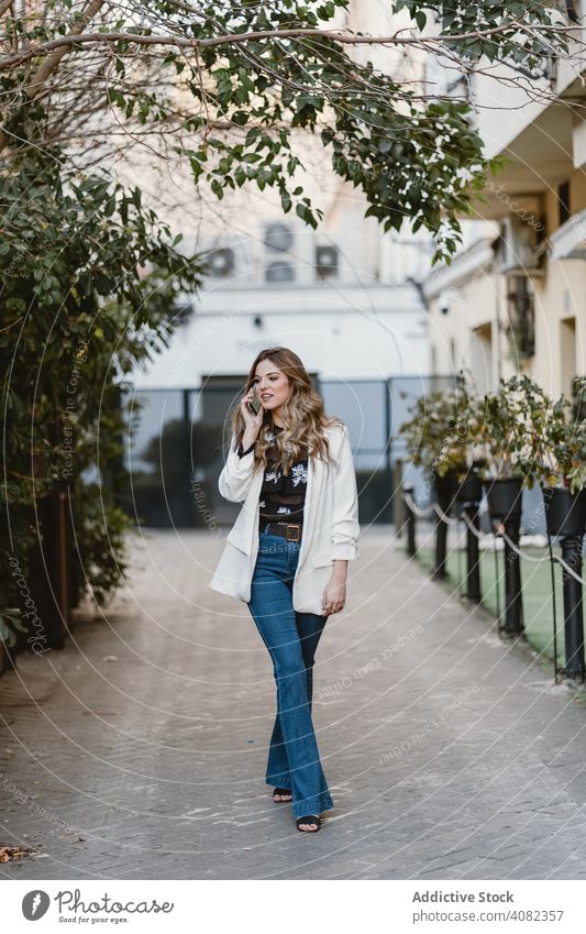 Lady talking phone on street woman smartphone walking city young urban lifestyle leisure sensual female trendy windy toothy joy elegant lady town casual gesture