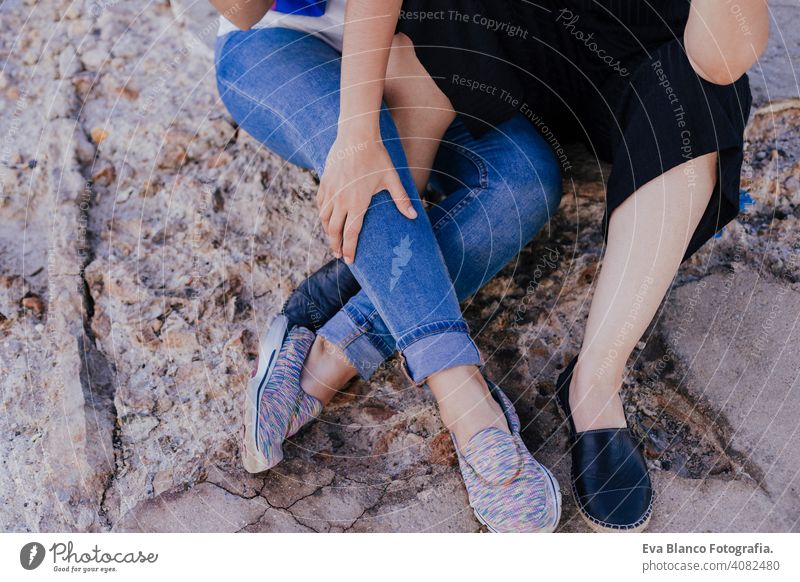 young unrecognizable lesbian couple sitting outdoors. Lifestyle and pride concept. love is love gay foot togetherness sex body white floor woman concepts adult