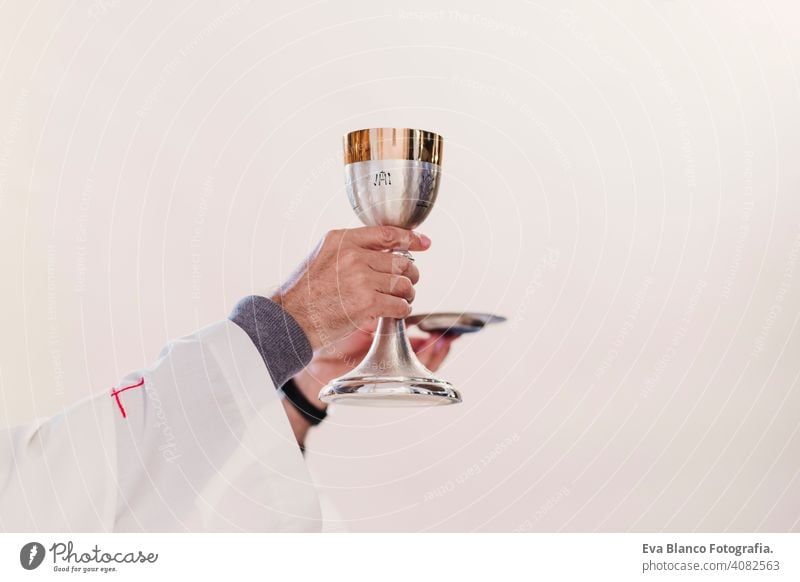 unrecognizable Priest holding the goblet during a wedding ceremony nuptial mass. Religion concept body sacrament liturgy catholic litany priest closeup interior