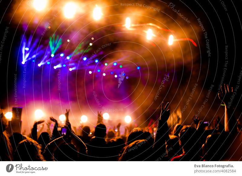 Picture of a lot of people enjoying night perfomance, large unrecognizable crowd dancing with raised up hands and mobile phones on concert. nightlife fan live