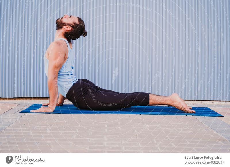 man in the city practicing yoga sport. blue background. healthy lifestyle urban muscular concentration position people young body meditating meditation beauty