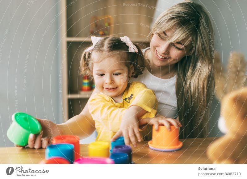 Mom and a laughing little girl play with colorful molds at the table at home. Time together, motherhood, parenthood child game preschool mom learning cute