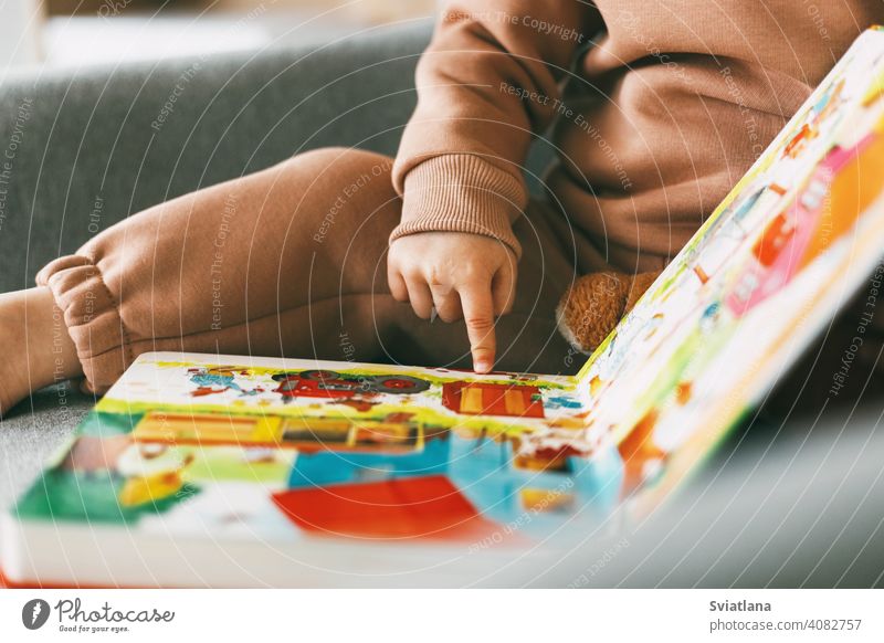 Close-up of a children's educational book with colored pictures in the hands of a little girl. Development, education, childhood sitting toddler happiness home