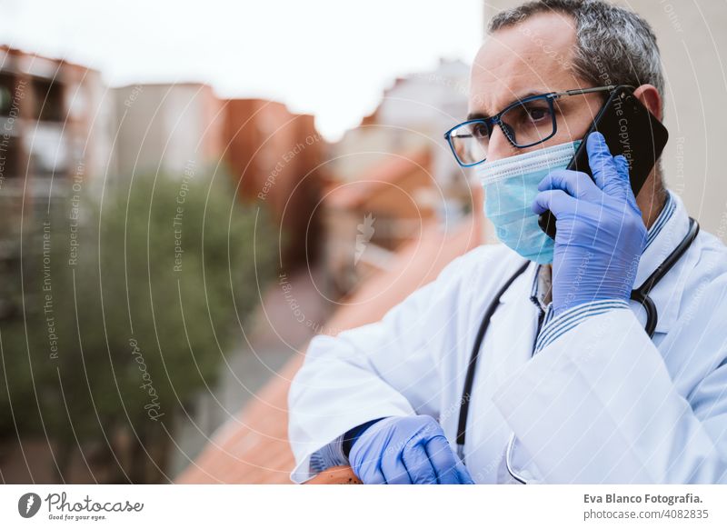 doctor man taking a break, using mobile phone. Wearing protective gloves, mask and stethoscope. coronavirus covid-19 concept corna virus protective mask