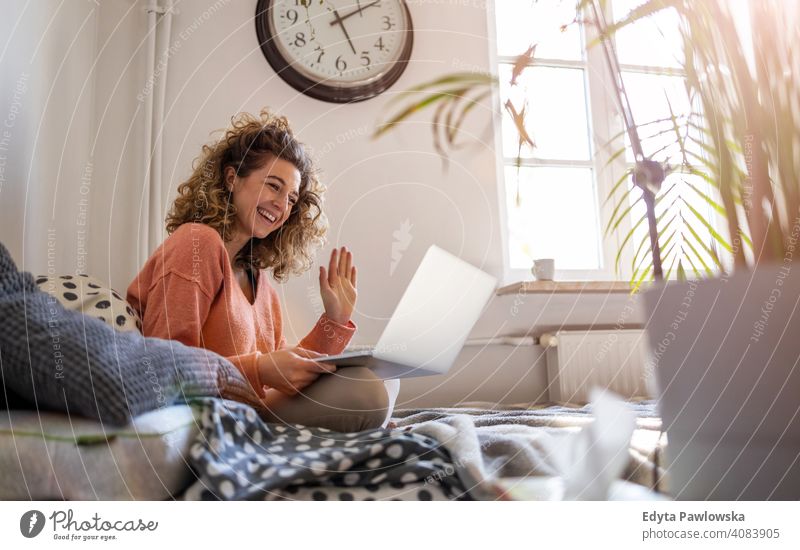 Young woman working in bed at home with laptop education learning studying homework book e-learning technology computer internet online communication wireless