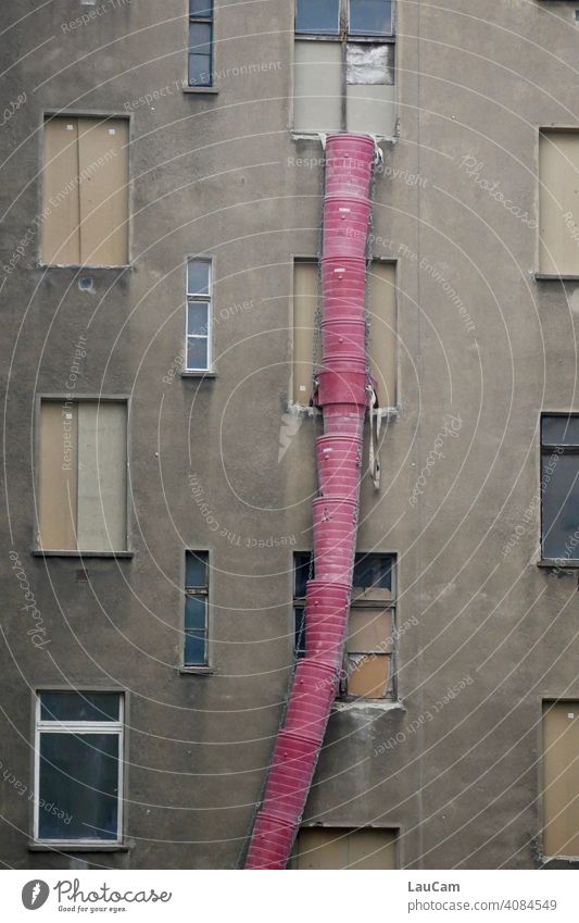 Red rubble slide in front of a grey house facade on a construction site in Prenzlauer Berg rubble chute rubbish Construction site grey in grey Gray