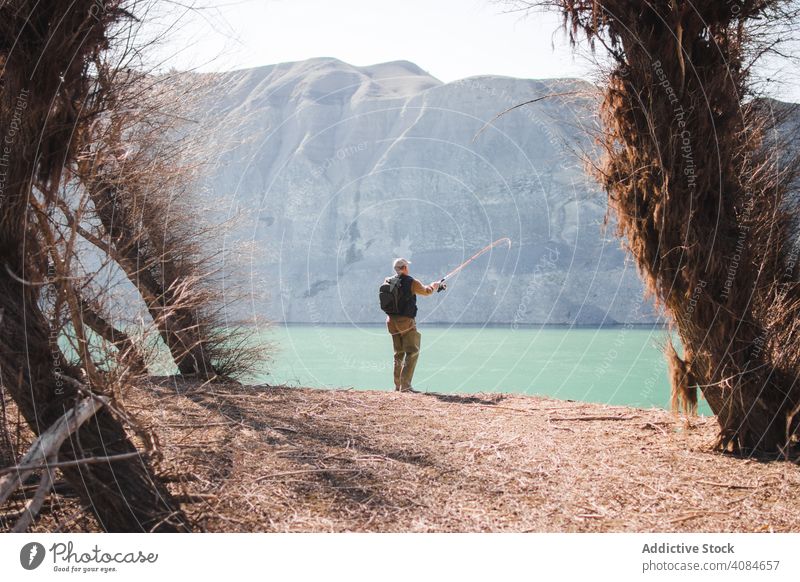 Man fishing near lake man nature rod leisure water activity hobby lifestyle coast catch recreation pond mountain sunny daytime landscape countryside pole rest