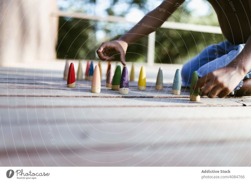 Crop black kid playing with cones boy sitting sunny daytime shirtless game colorful lifestyle leisure rest relax african american ethnic little fun child wooden