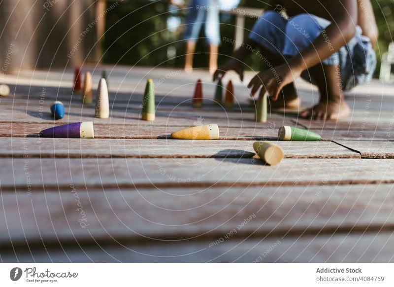 Crop black kid playing with cones boy sitting sunny daytime shirtless game colorful lifestyle leisure rest relax african american ethnic little fun child wooden