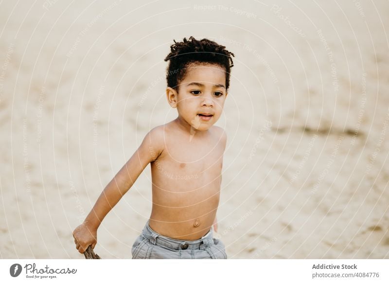 Black boy playing on beach sea sticks fun summer water shirtless barefoot kid child siblings game happy weekend lifestyle leisure shore coast ocean wet joy