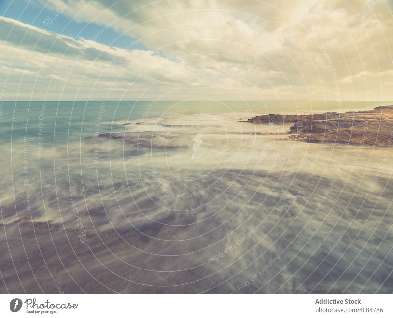 Rocky seashore under blue sky landscape coastline ocean rocks dusk cloudscape stone marine ripples weather horizontal outdoors copy space stones waves nature