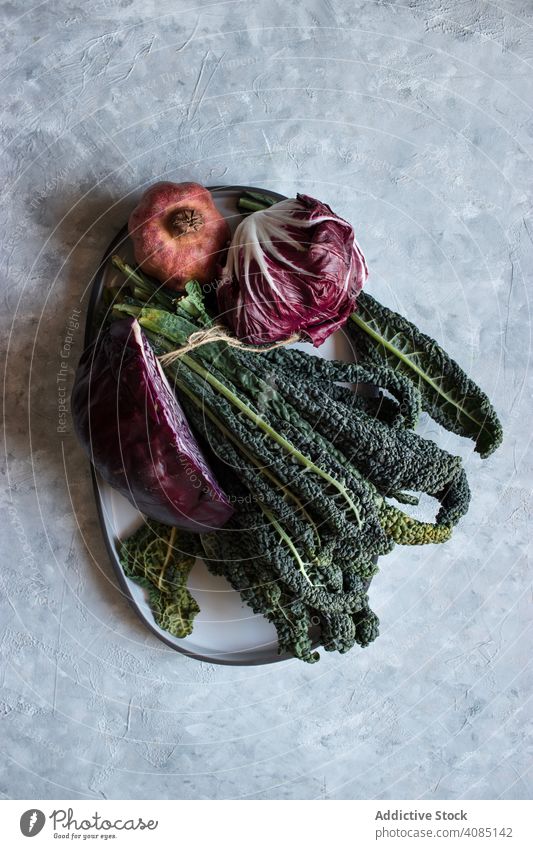 Pomegranate near red cabbage and kale pomegranate plate table leaves vegan ingredients fresh vegetable fruit healthy salad raw organic natural vitamin cuisine