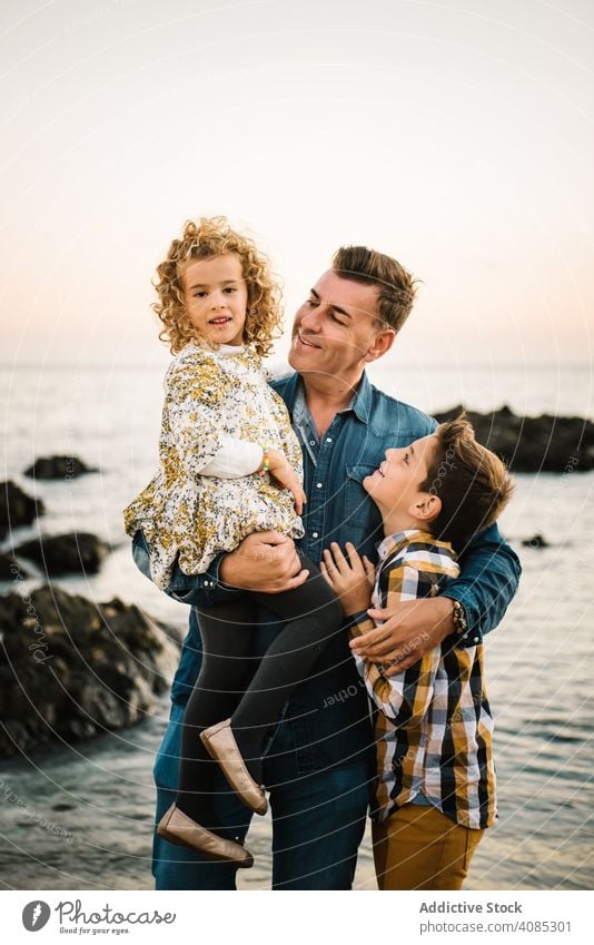 Father with her children at beach family seaside vacation kids smiling hug hugging embrace father man middle-aged daughter son girl togetherness summer sand