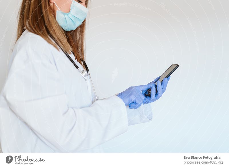 portrait of doctor woman wearing protective mask and gloves indoors. Using mobile phone. Corona virus concept technology internet wireless cloe up professional