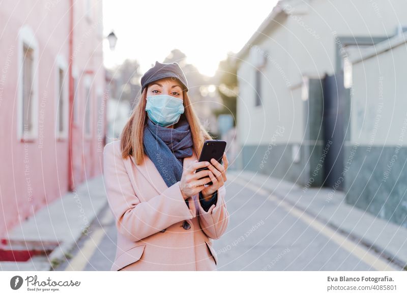 caucasian woman in the street wearing protective mask and using mobile phone. corona virus concept outdoors technology internet public adult infection space