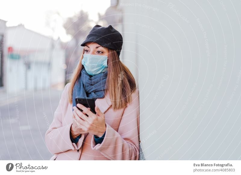 caucasian woman in the street wearing protective mask and using mobile phone. corona virus concept outdoors technology internet public adult infection space