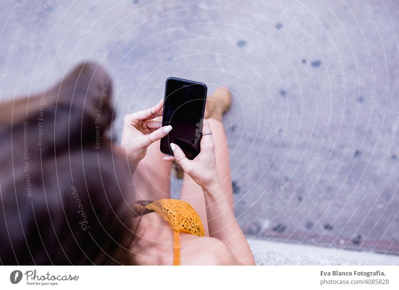 young blonde beautiful woman at the street using mobile phone and smiling. Lifestyle outdoors. Summertime, Green background smart urban happy people run modern