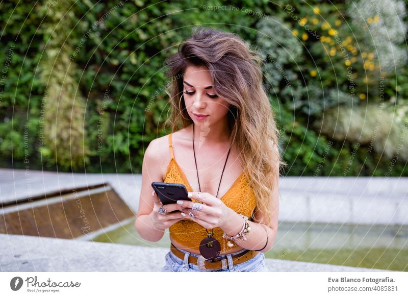 young blonde beautiful woman at the street using mobile phone and smiling. Lifestyle outdoors. Summertime, Green background smart urban happy people run modern