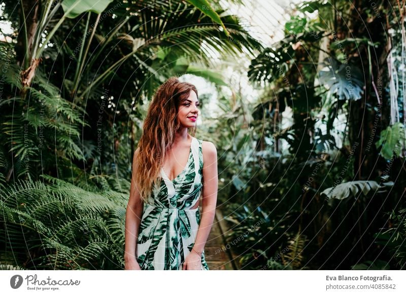 portrait of beautiful blonde young woman smiling at sunset in a green house surrounded by tropical plants. Happiness and lifestyle concept caucasian toothy cute