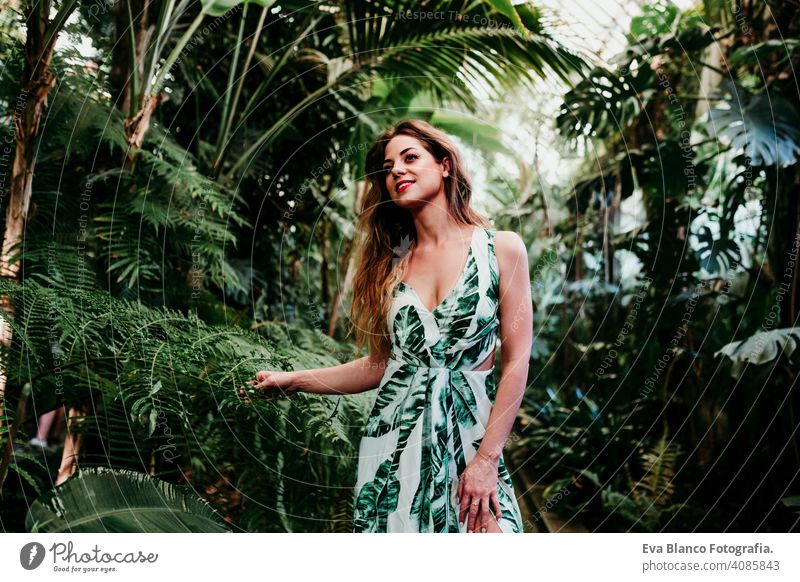 portrait of beautiful blonde young woman smiling at sunset in a green house surrounded by tropical plants. Happiness and lifestyle concept caucasian toothy cute