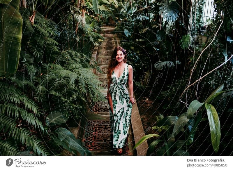 portrait of beautiful blonde young woman smiling at sunset in a green house surrounded by tropical plants. Happiness and lifestyle concept caucasian toothy cute