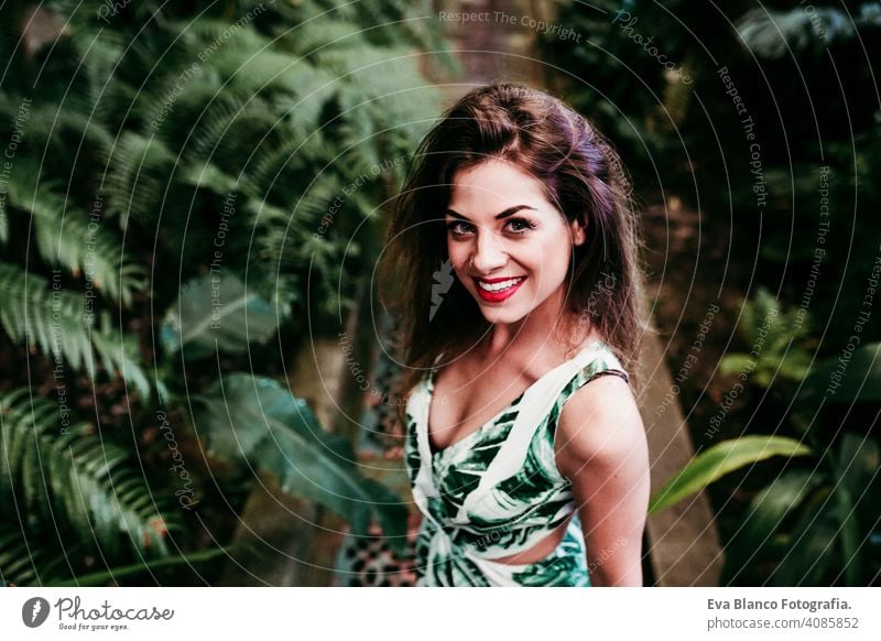 portrait of beautiful blonde young woman smiling at sunset in a green house surrounded by tropical plants. Happiness and lifestyle concept caucasian toothy cute