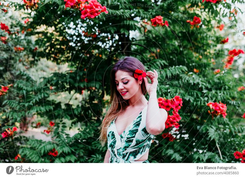 portrait of beautiful blonde young woman smiling at sunset. Playing with red flowers. Happiness and lifestyle concept outdoors caucasian toothy cute happy girl