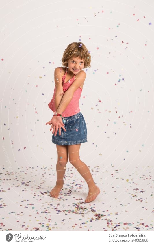 kid playing with confetti in the studio. Fun, lifestyle, little girl portrait. indoors, confetti on the floor. white  background fun child cute