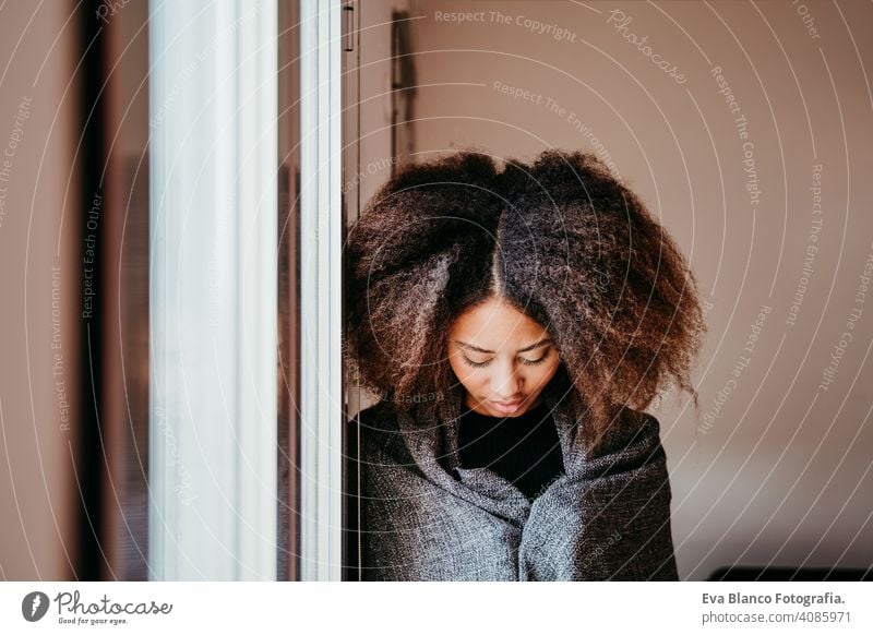 portrait of beautiful afro american young woman by the window. Lifestyle indoors coffee home ethnic mixed race tea autumn winter blanket daytime african smiling