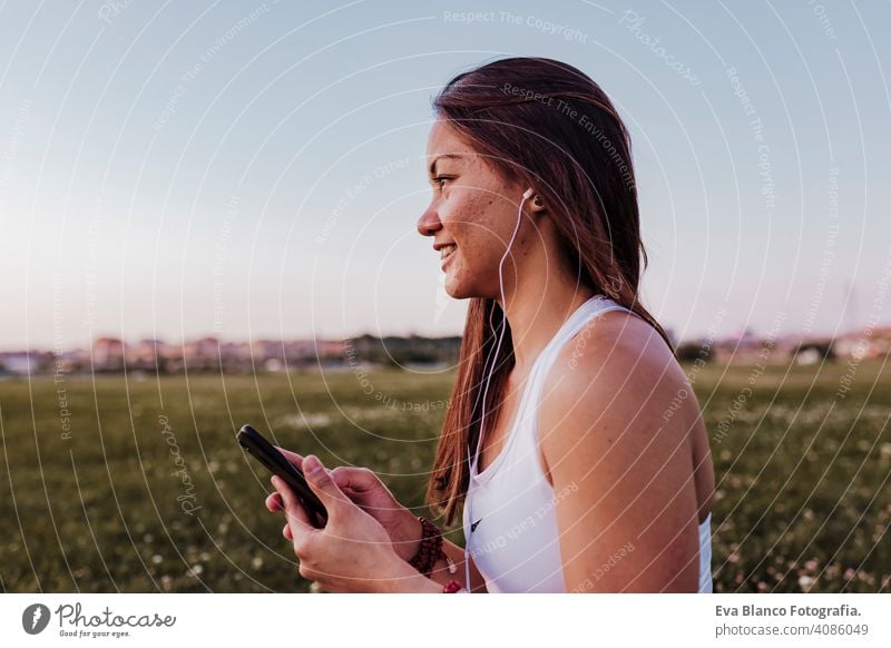 young beautiful asian woman relaxed after her yoga practice listening to music on earphones and mobile phone. Yoga and healthy lifestyle concept summer happy