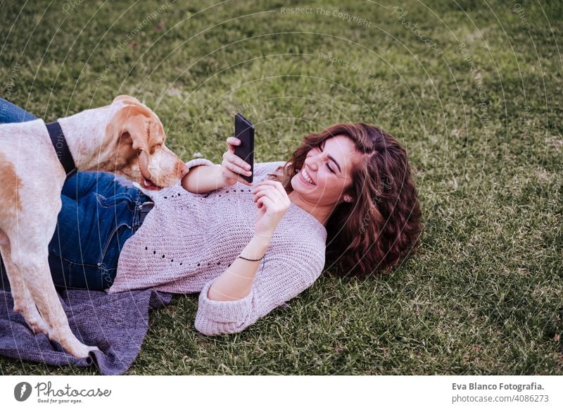 young woman taking a selfie with mobile phone with her dog at the park. autumn season picture photo technology outdoors love pet owner sunny beautiful happy