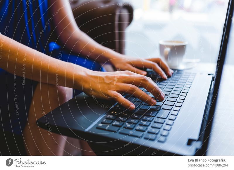 top view of a young beautiful woman writing on laptop, coffee besides. Casual blue dress. Modern life indoors hipster college computer display notebook looking