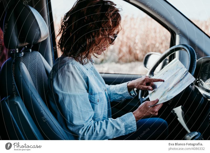 young beautiful woman reading a map in a car. travel concept driving sunny sunglasses traveling wheel drive hire sharing new traffic maintenance expensive