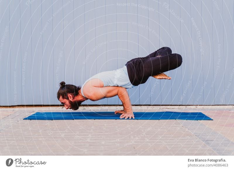 man in the city practicing yoga sport. blue background. healthy lifestyle outdoors muscular young handsome hispanic caucasian sportswear urban concentration