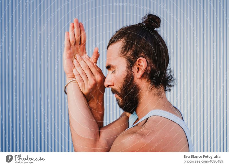 man in the city practicing yoga sport. blue background. healthy lifestyle outdoors muscular young handsome hispanic caucasian sportswear urban concentration