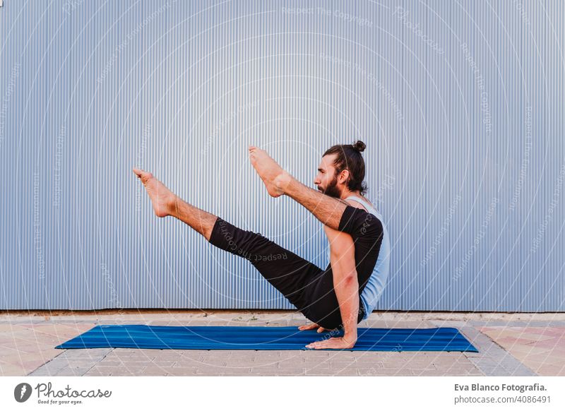 man in the city practicing yoga sport. blue background. healthy lifestyle outdoors muscular young handsome hispanic caucasian sportswear urban concentration