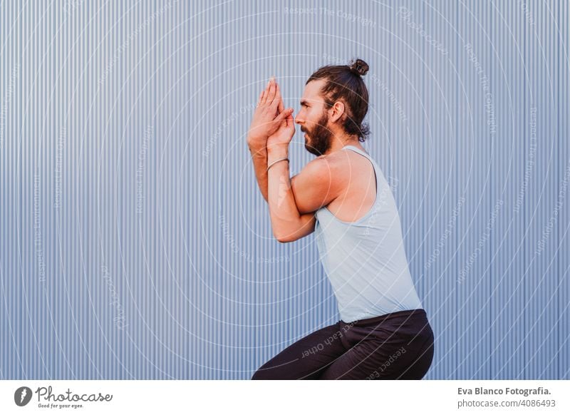 man in the city practicing yoga sport. blue background. healthy lifestyle outdoors muscular young handsome hispanic caucasian sportswear urban concentration