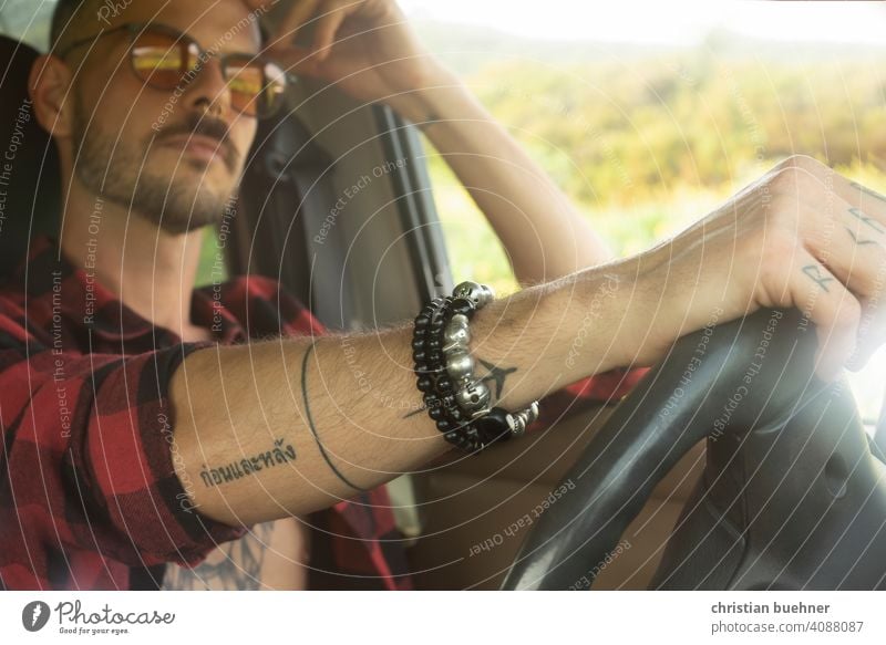 man in car - hand on steering wheel Man portrait car interior sunglasses Car driver arm jewellery Bangle Cool Model Driving 30 years naked torso relaxed Summer