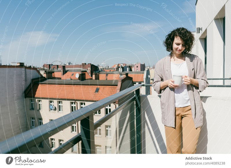 Elegant woman enjoying sun at terrace balcony cup coffee railing leaning closed eyes sunlight relaxed young female cheerful beautiful attractive pretty charming