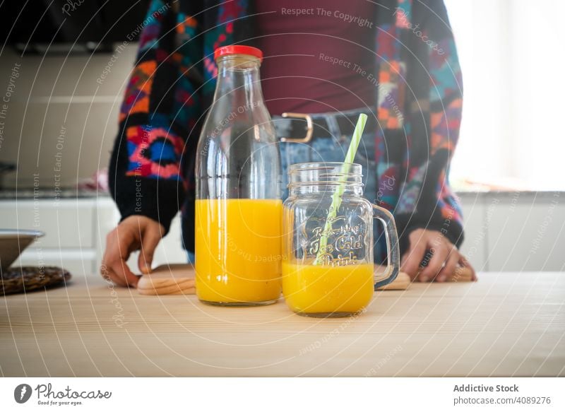 Orange juice in kitchen countertop citrus jar woman orange straws table fresh drink healthy beverage refreshment sweet ripe slice piece mug wooden rustic