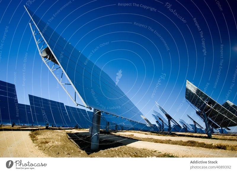 Solar panels against blue sky solar power station reflecting photovoltaic cloudless sunny field cells daytime energy electricity technology shiny weather