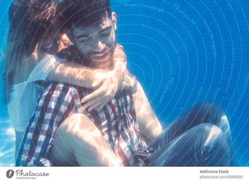 Dressed Couple embracing underwater couple pool swimming together relationship leisure summertime love adult fun vacation emotion cheerful hugging resort