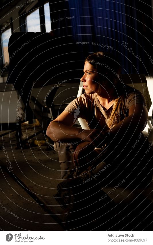 Female soldier on floor of military vehicle woman serious looking away sitting shabby army strong uniform camouflage female transport forces thinking dreamy