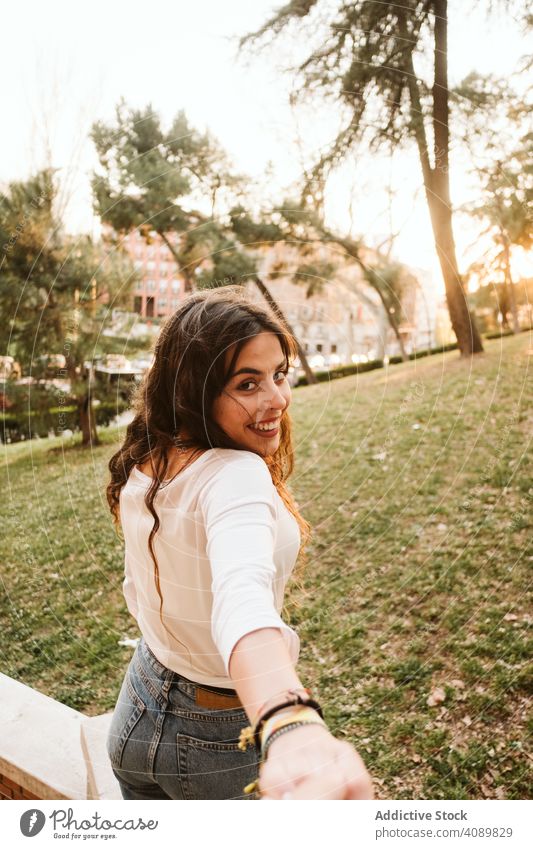 Cheerful woman leading way on city street follow me smiling holding hand road sunset evening young female travel trip tourism sundown dusk twilight town