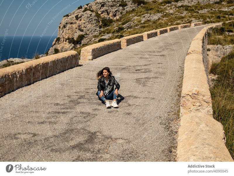 Woman sitting on stony path in countryside woman hill sunny daytime young casual female nature way rock lifestyle leisure travel trip freedom carefree lady