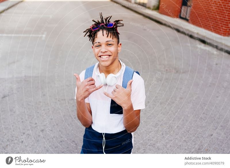 Young cheerful black male standing on street man happy city headphones shaka sign hipster young african american ethnic smiling joy handsome successful cool guy