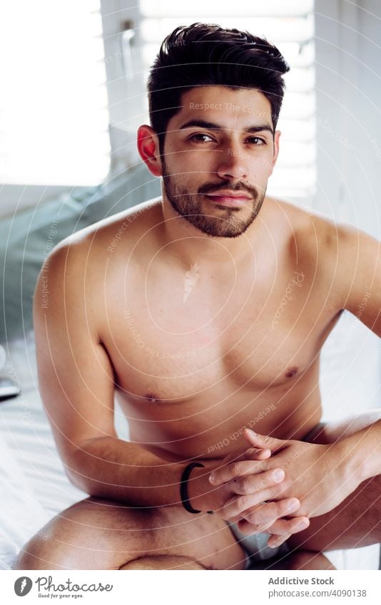 Young sexy pensive man sitting on bed underwear thoughtful books young male handsome successful cool naked hot brutal hunk macho muscular fit stylish hairstyle